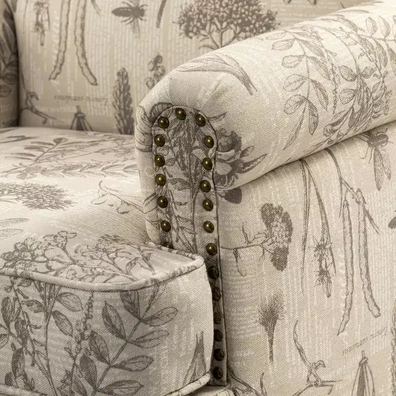 Fauteuil rembourré en bois avec motif floral, accoudoirs à panneaux et dossier en forme de bosse de chameau.